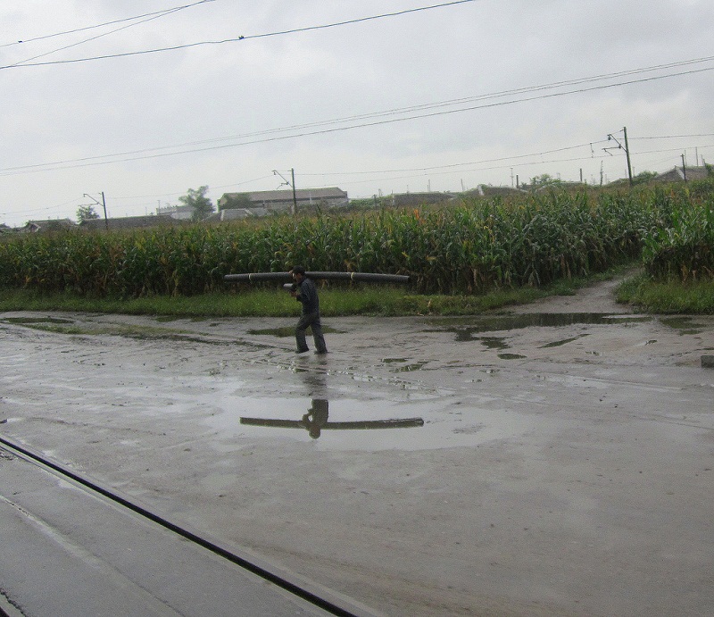 aNorth Korea industrial area near Hamhung guy hauling pipe in pouring rain.jpg