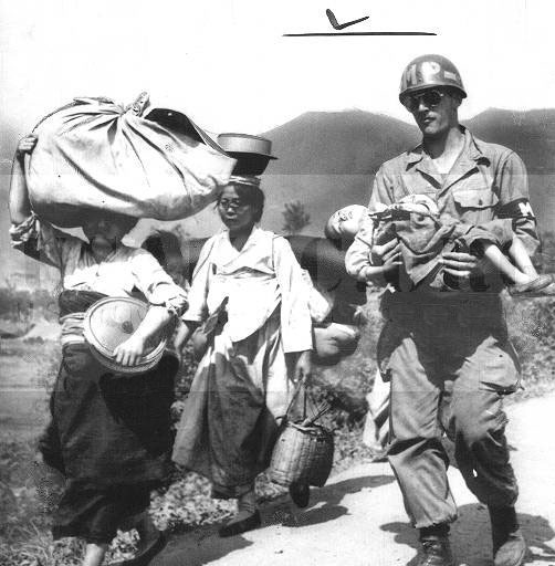 American MP carrying a sleeping child as he helps civilian refugees evacuate a village near Hwachon, Korea.jpg
